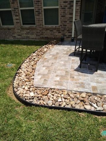 A two-story house with a green lawn, surrounded by large, lush trees under a bright blue, partly cloudy sky.