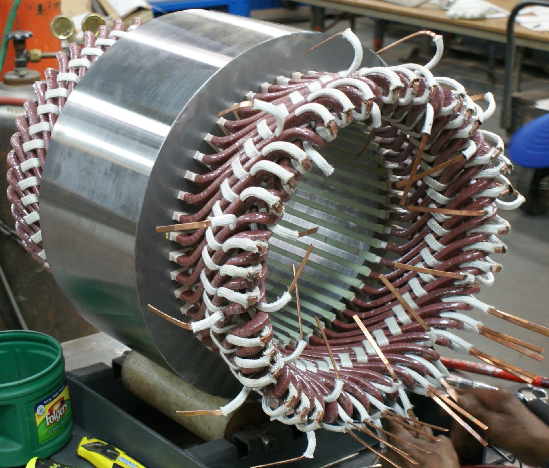 A person is working on an electric motor with a bucket of scotch brite in the background