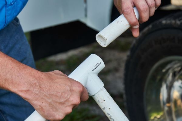 A man is holding two plastic pipes in his hands.