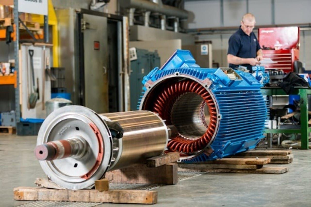 A man is working on an electric motor in a factory.