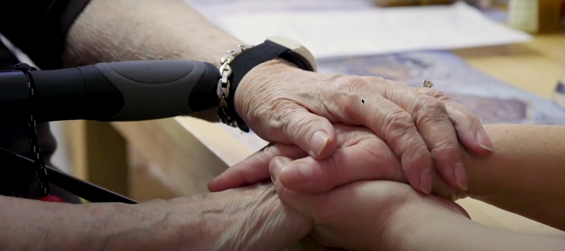 An elderly woman is holding the hand of a younger woman.