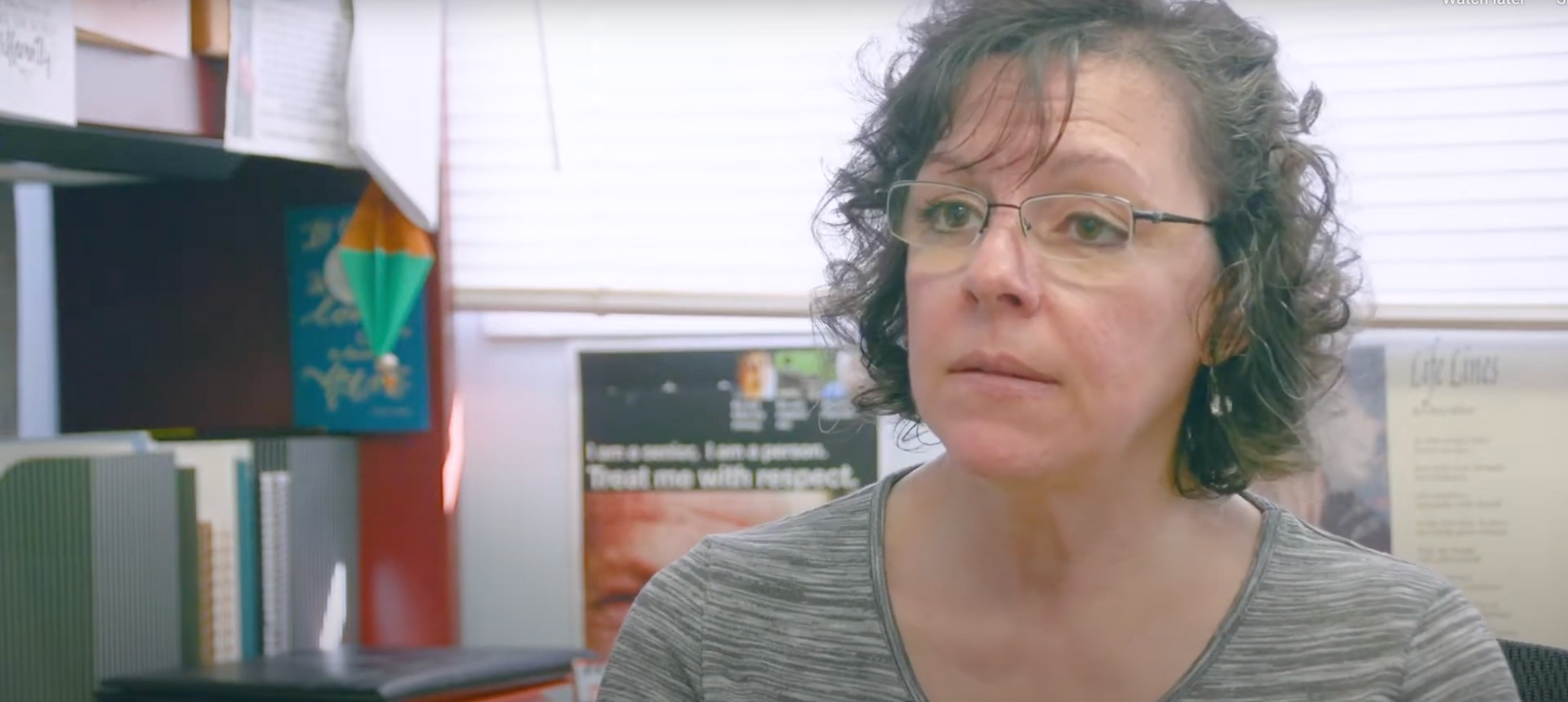 Une femme portant des lunettes est assise devant une fenêtre dans un bureau.