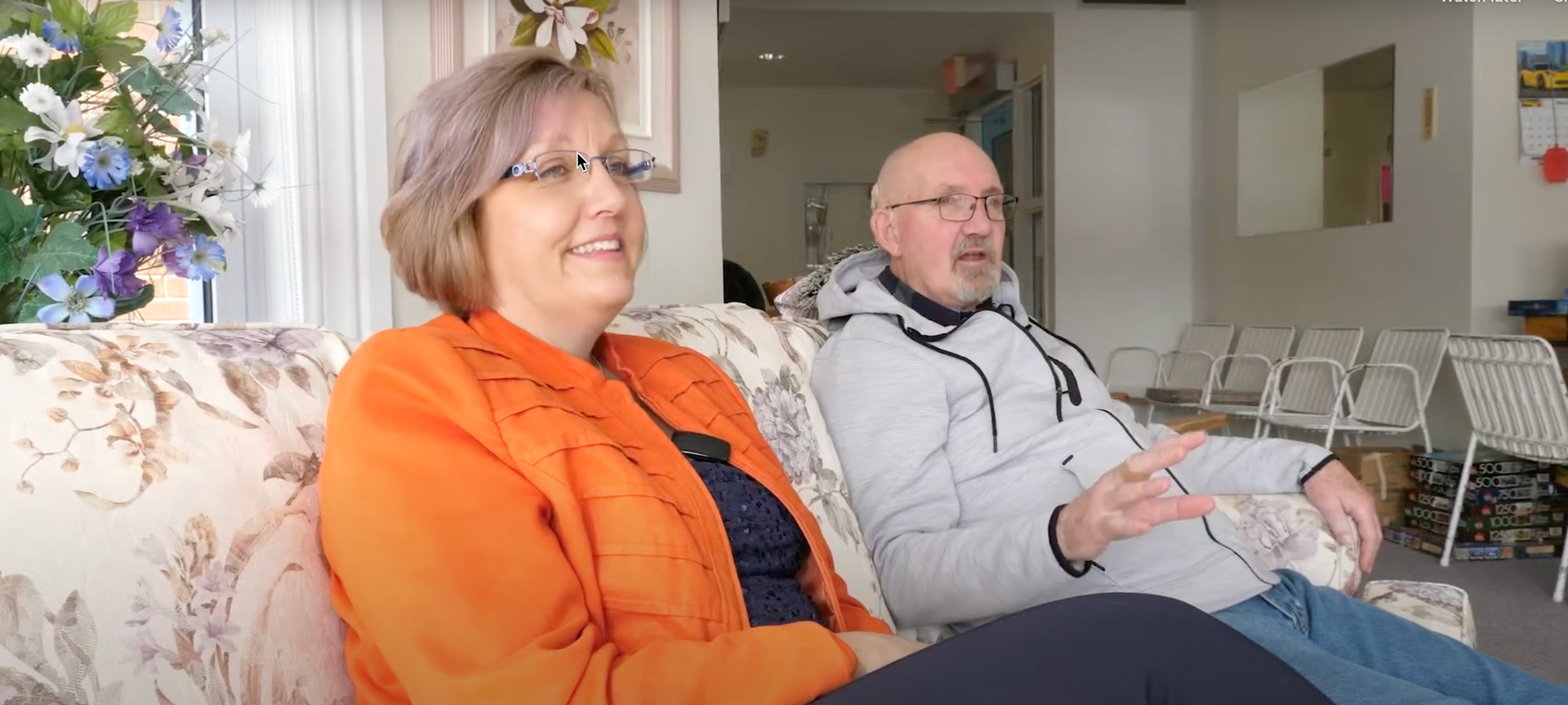 A man and a woman are sitting on a couch in a living room.