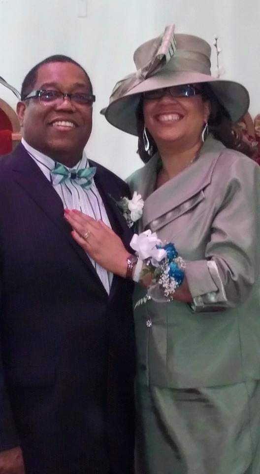 a man and woman are posing for a picture and the woman is wearing a hat