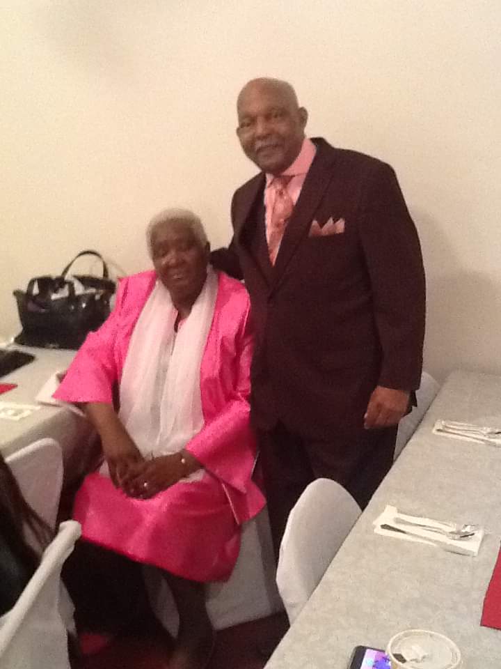 a man in a suit stands next to a woman in a pink dress