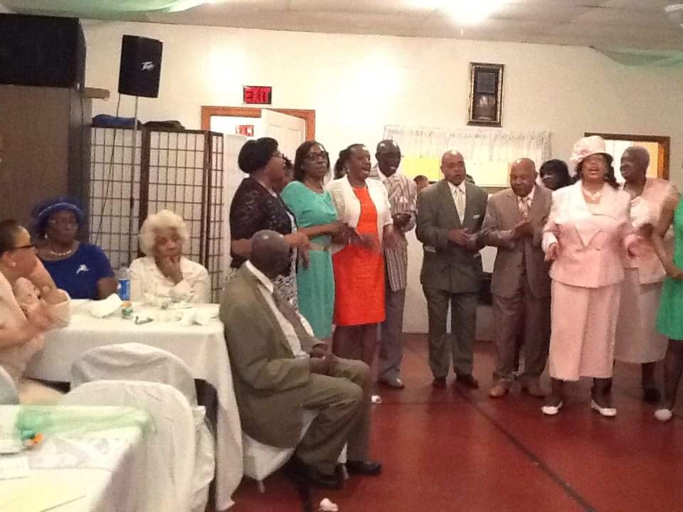 a group of people standing in a room with tables and chairs