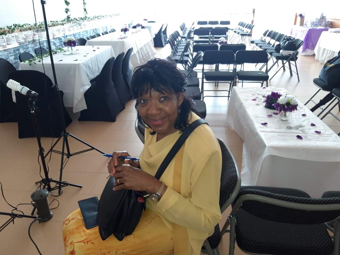 a woman in a yellow dress is sitting in a room with tables and chairs