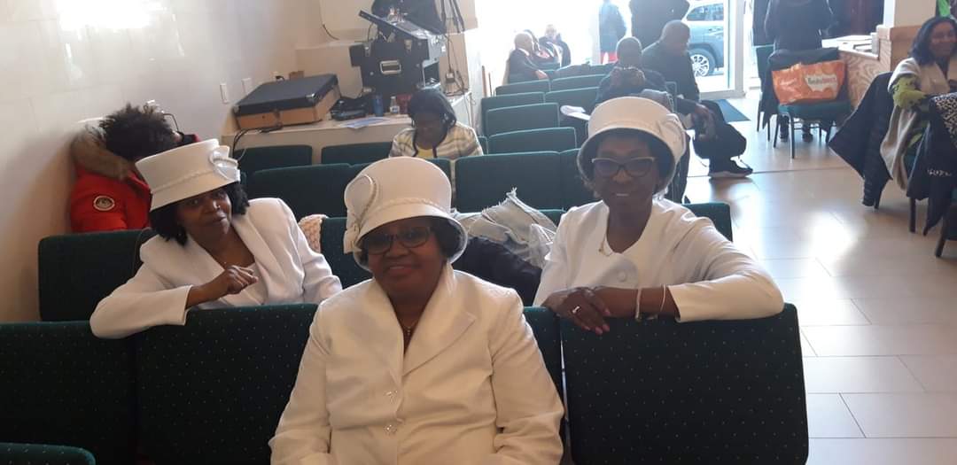 a group of women wearing white hats are sitting in a waiting room .