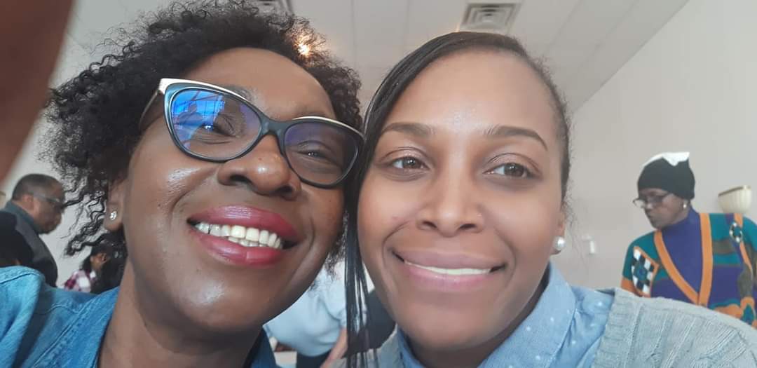 two women are posing for a picture together and smiling for the camera .