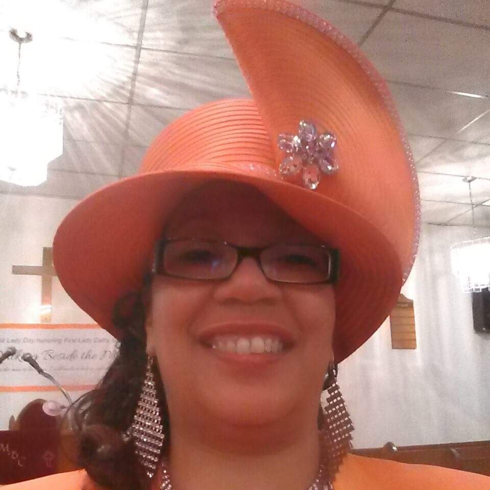 a woman wearing an orange hat and glasses is smiling