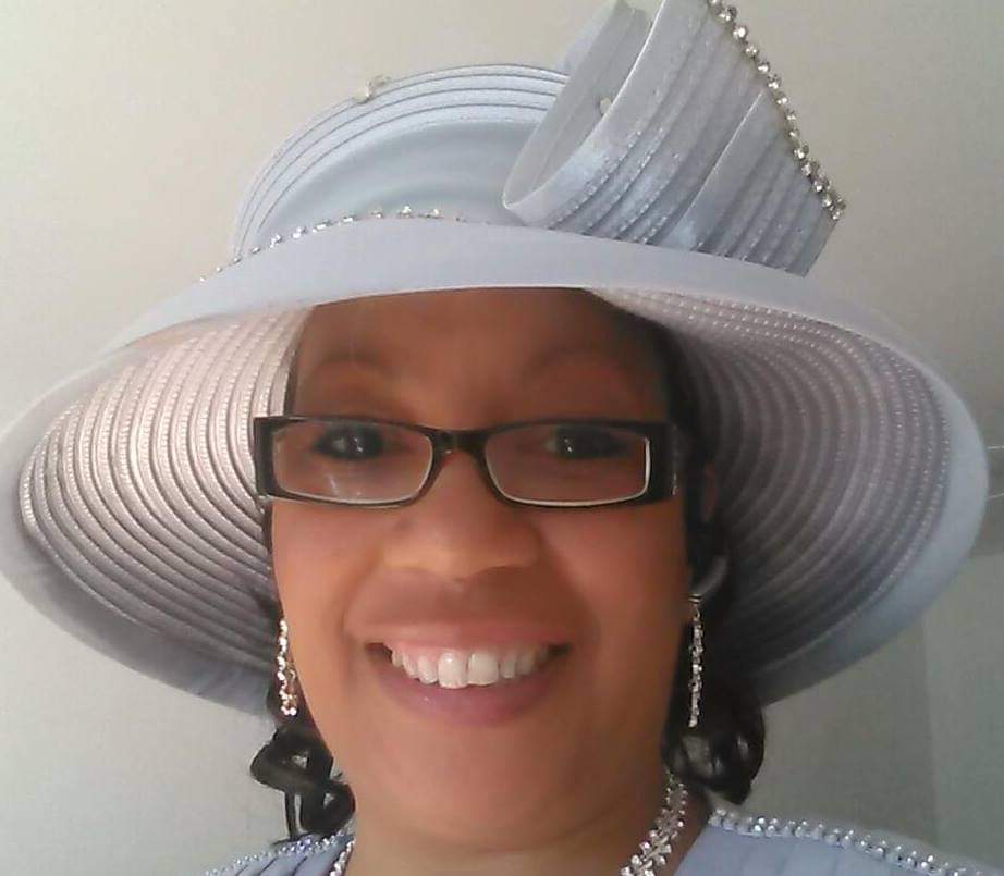 a woman wearing glasses and a hat smiles for the camera