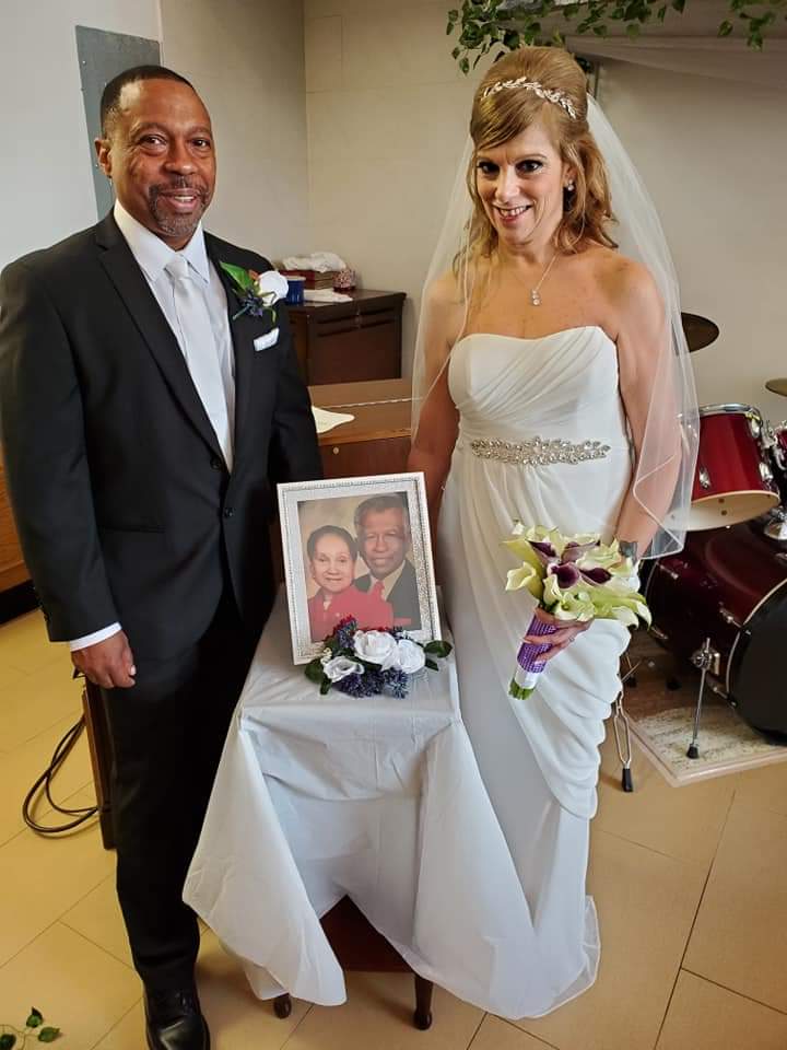 a bride and groom are posing for a picture in front of a drum set .