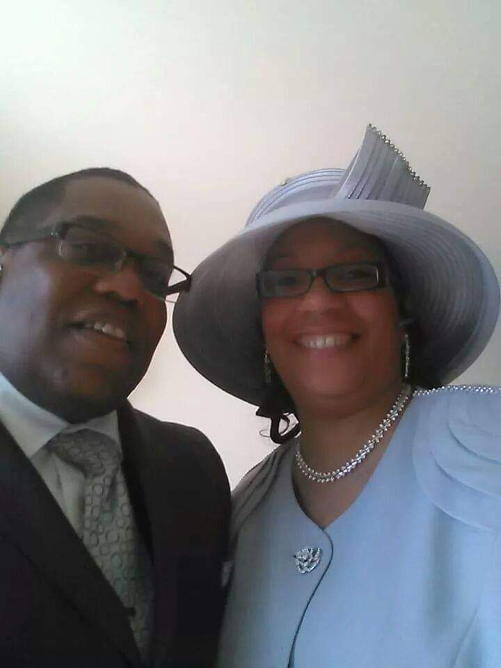 a man and woman are posing for a picture and the woman is wearing a hat