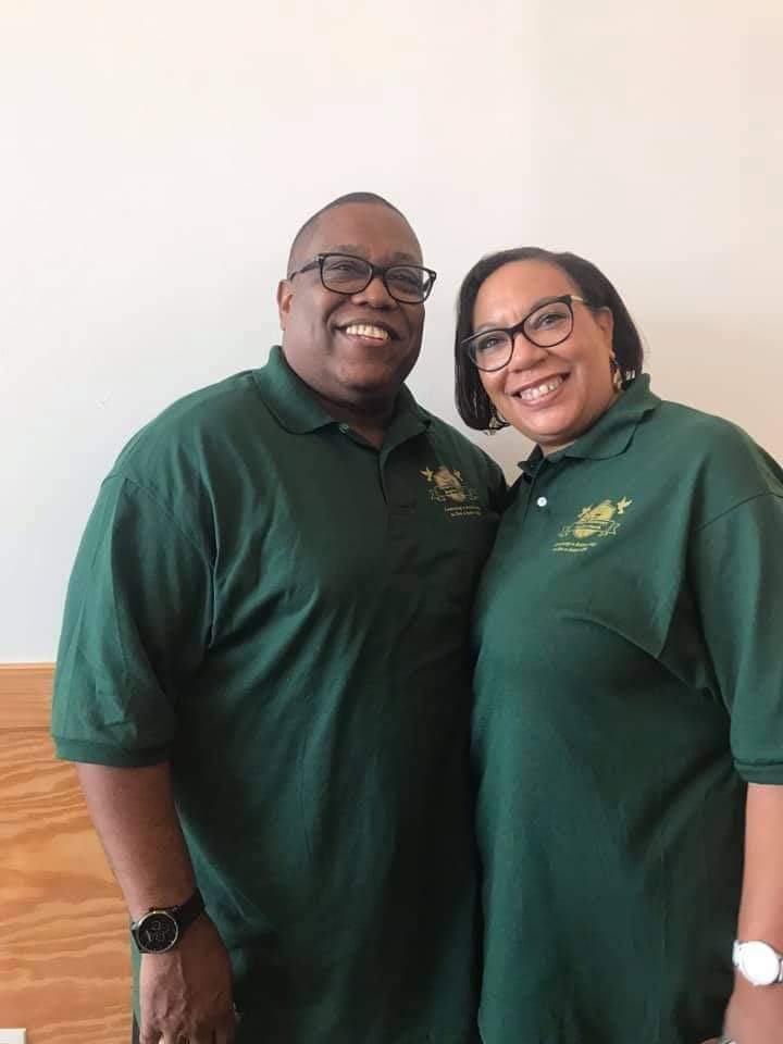 a man and a woman are posing for a picture while wearing green shirts .