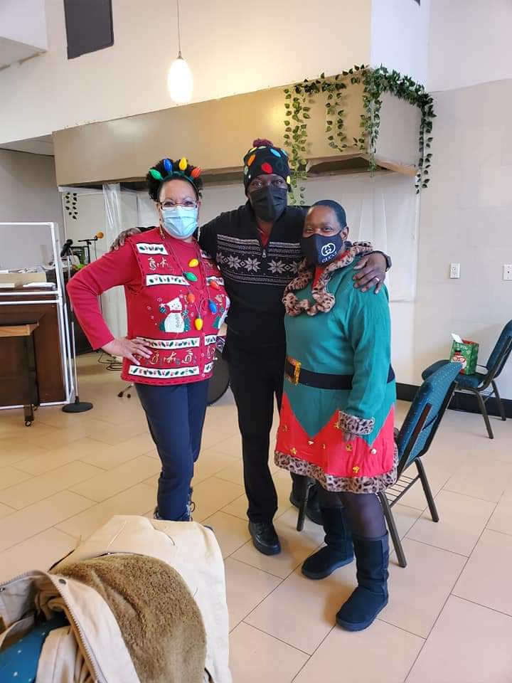 a group of people wearing christmas sweaters and masks are posing for a picture .