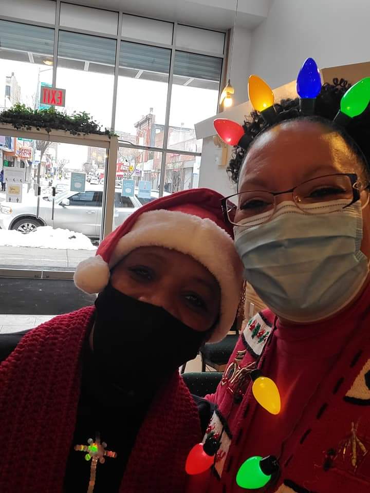 two women wearing masks and santa hats pose for a picture