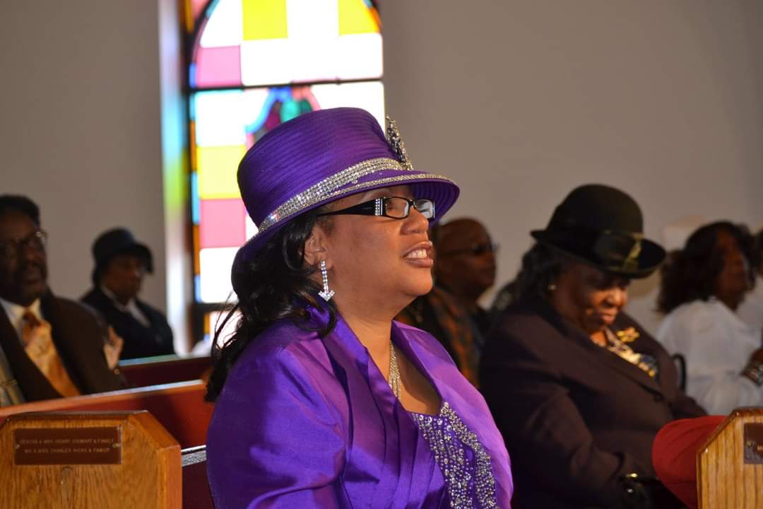 a woman in a purple hat is sitting in a church