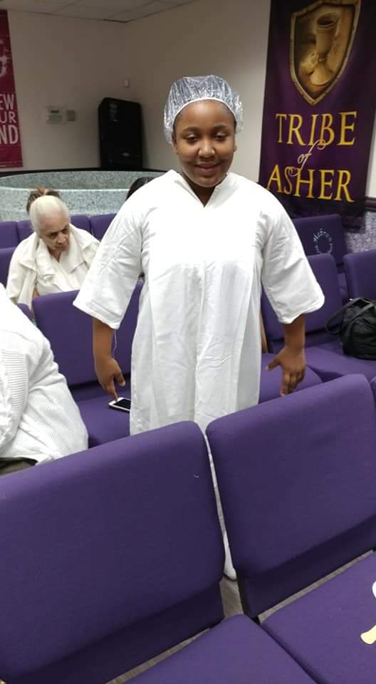 a woman in a white robe is standing in front of purple chairs .