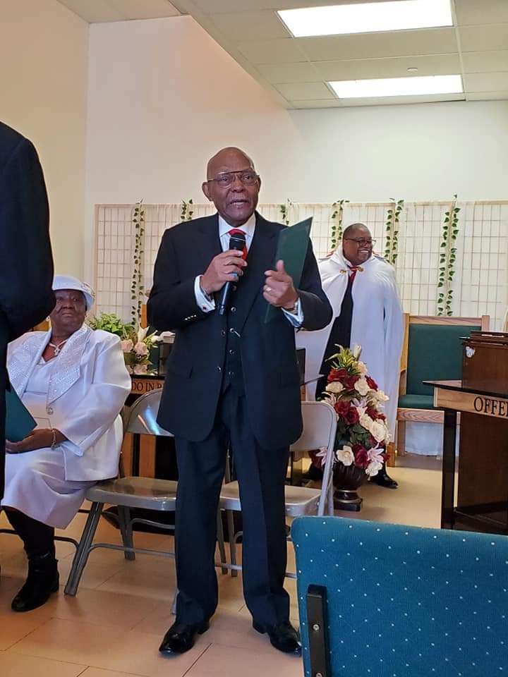 a man in a suit is standing in front of a microphone in a church .