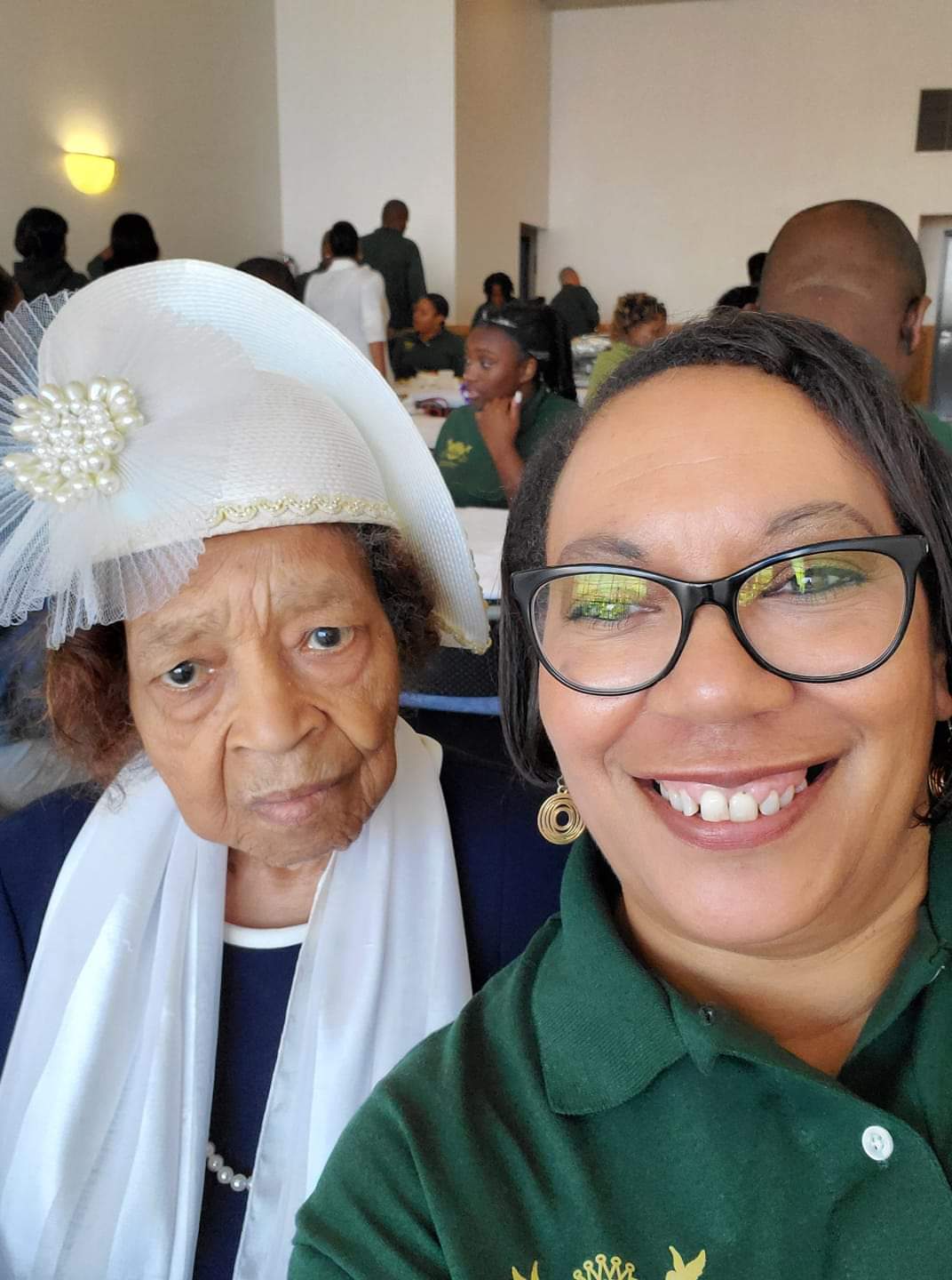a woman is taking a selfie with an older woman wearing a white hat and glasses .