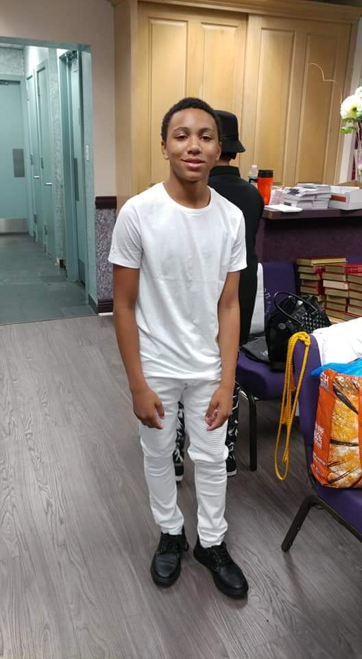 a young man in a white shirt and white pants is standing in a room .