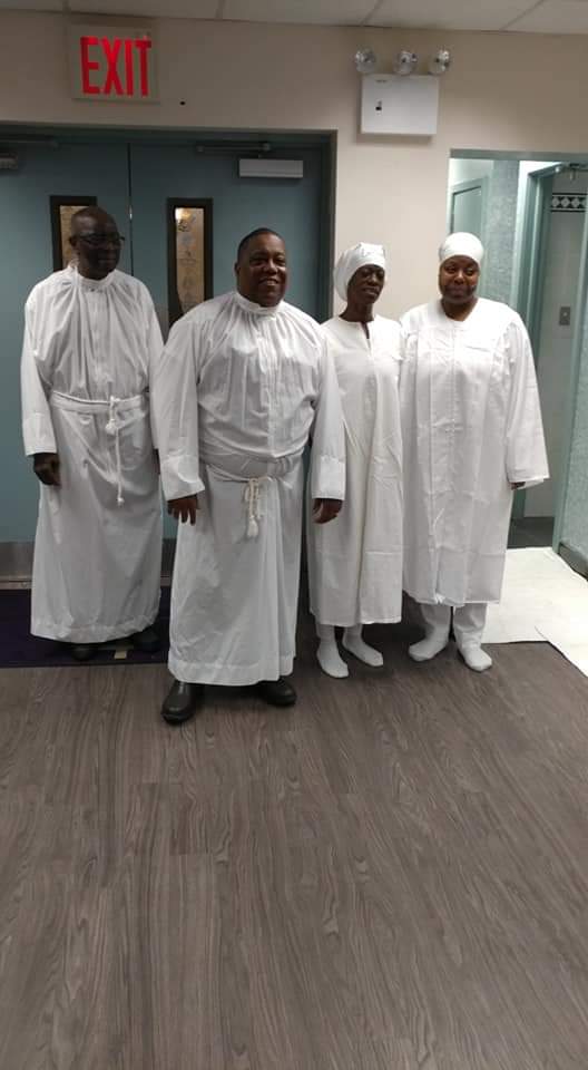 a group of people in white robes are standing next to each other in a room .