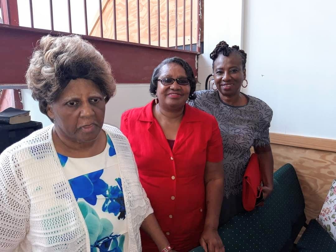 three women are standing next to each other in a room .