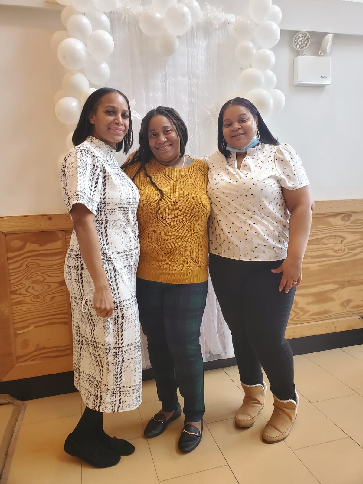 three women are posing for a picture in front of balloons .