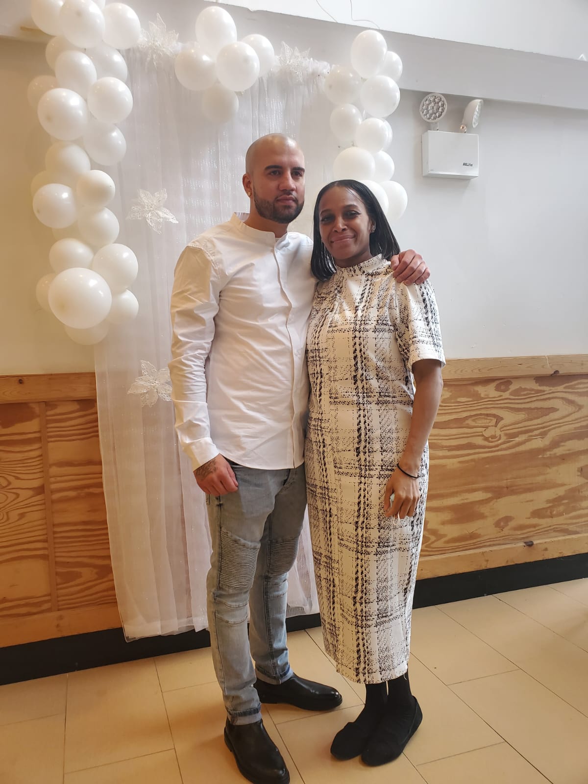 a man and a woman are posing for a picture in front of balloons .