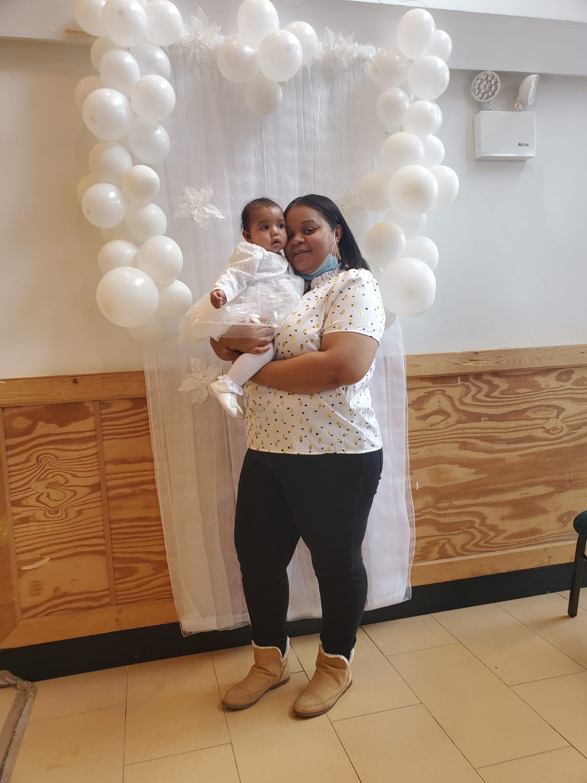 a woman is holding a baby in her arms in front of balloons .