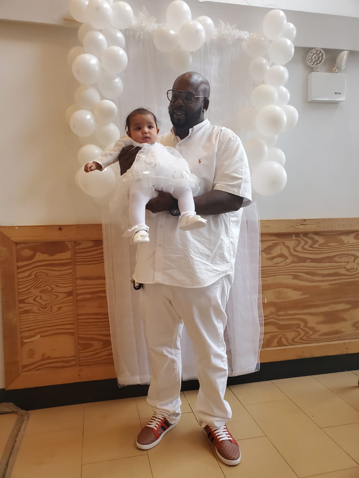 a man is holding a baby in his arms in front of balloons .