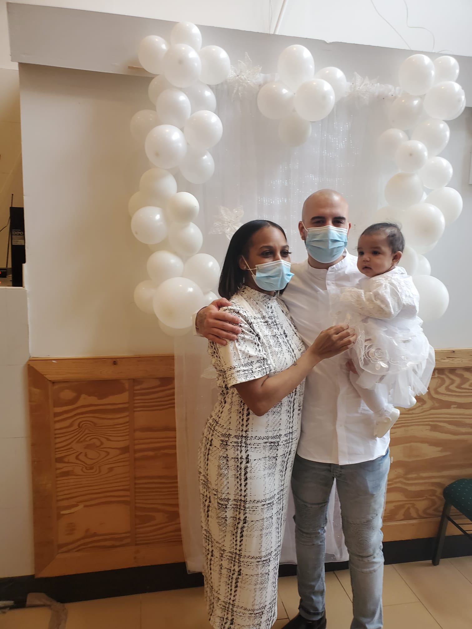 a man and a woman are holding a baby in front of balloons .
