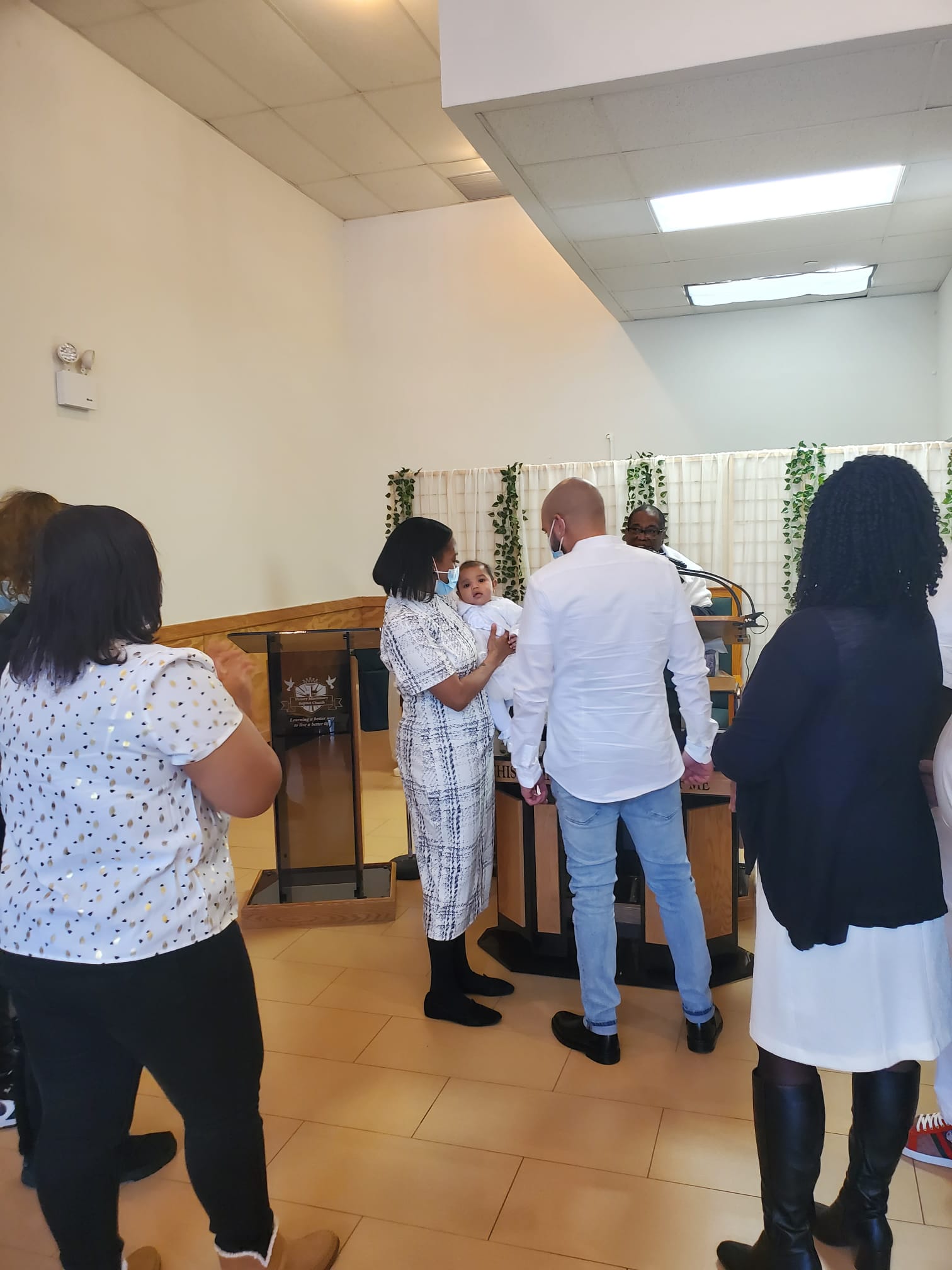 a group of people are standing in a room holding a baby .