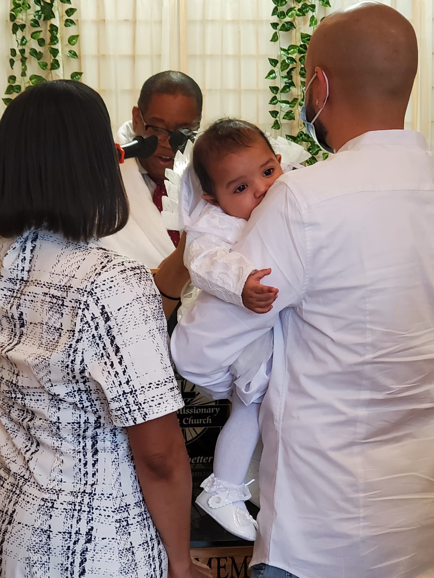 a man is holding a baby in his arms while a woman looks on .