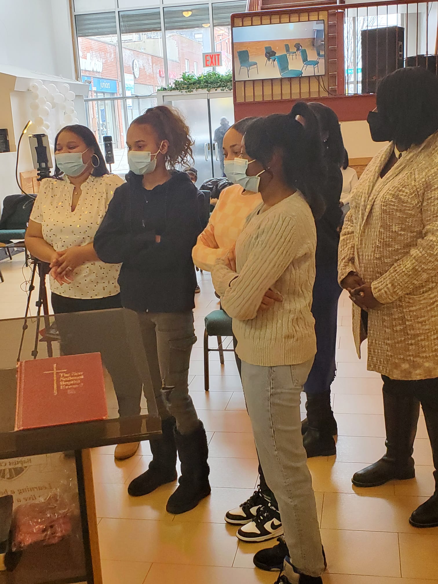 a group of people wearing face masks are standing in a room .