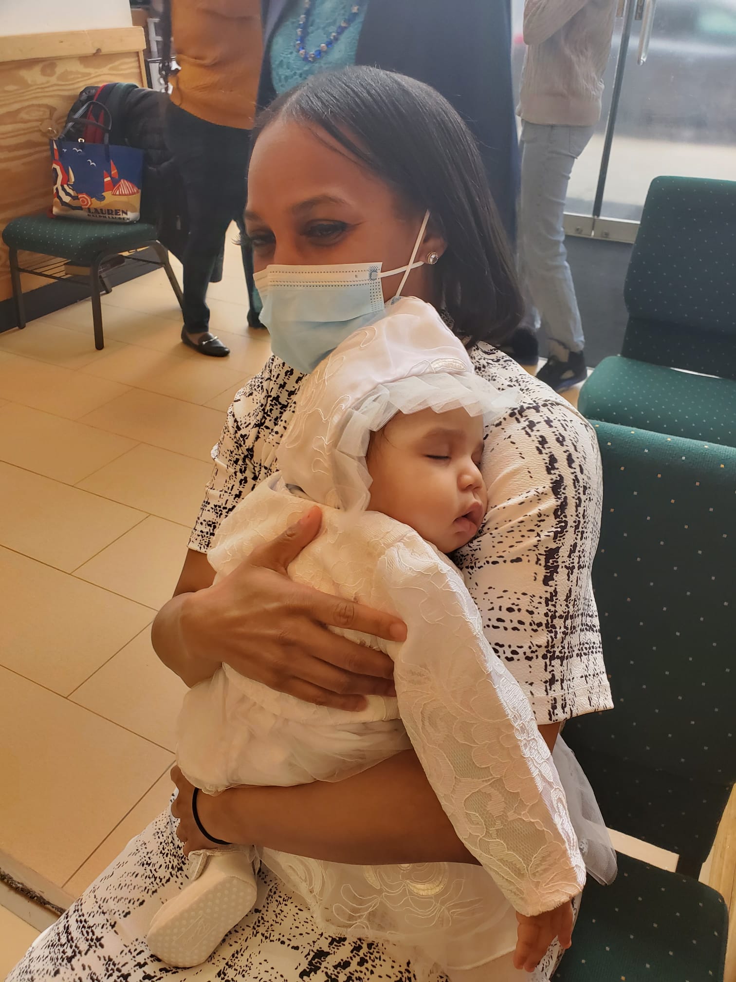 a woman wearing a mask is holding a baby in her arms .