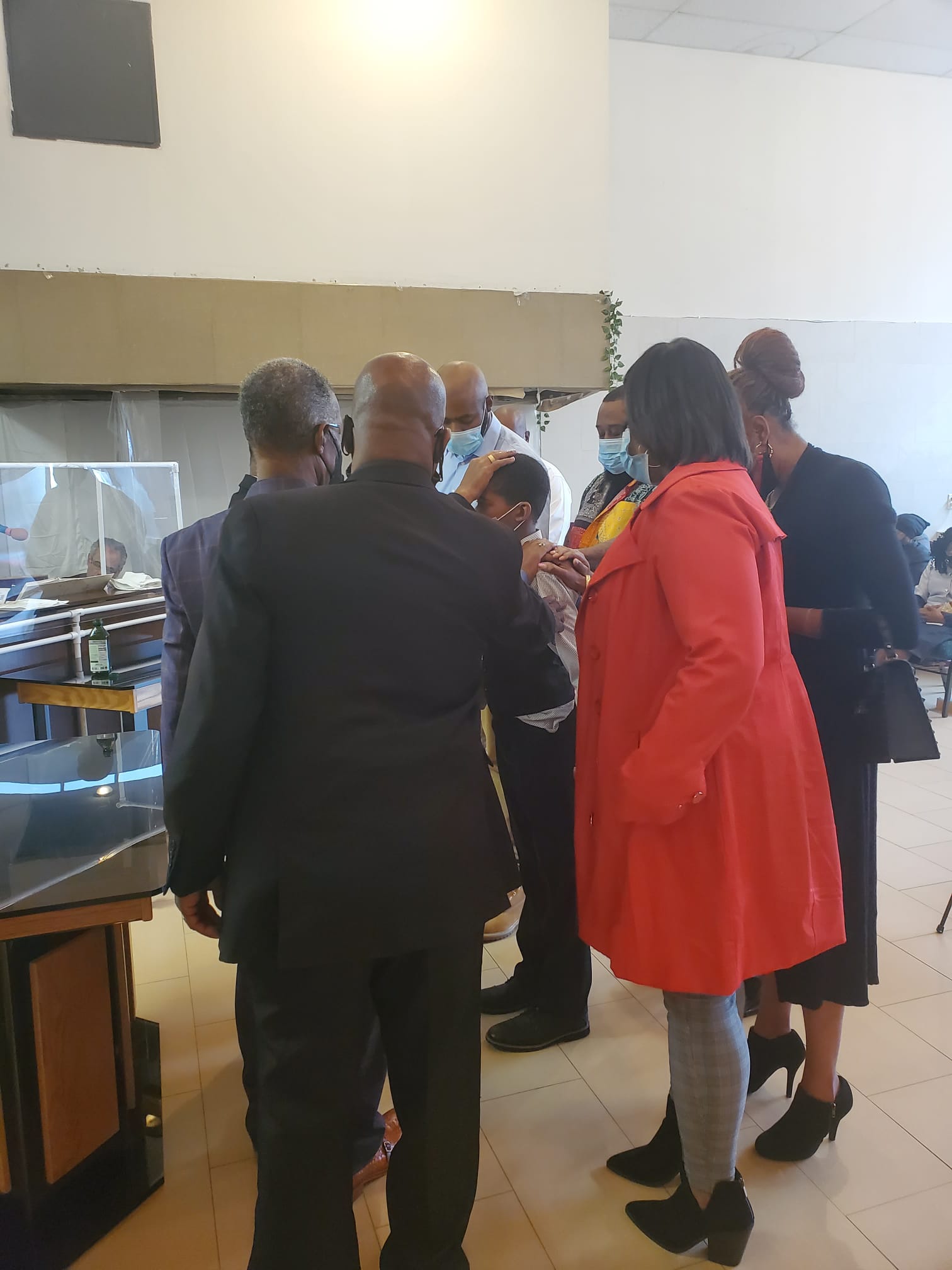 a group of people are standing in a room talking to each other .