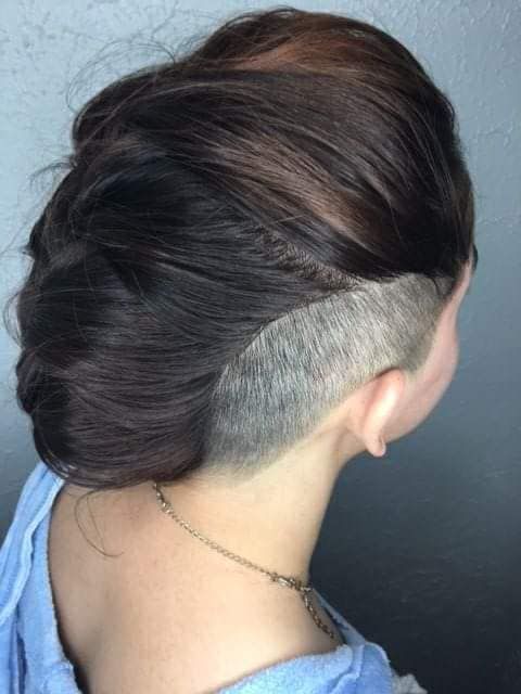 Woman with dark hair styled up, shaved side undercut.
