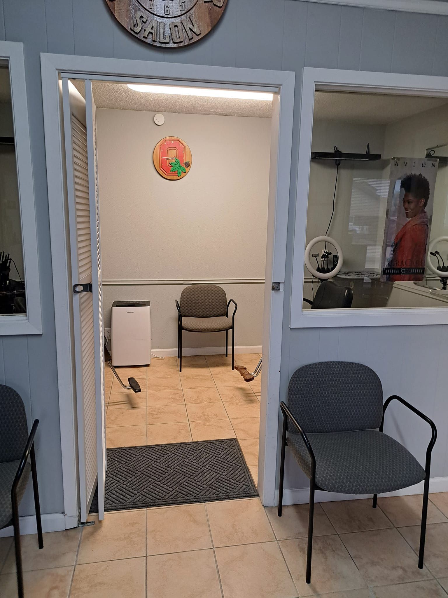 Waiting room with gray chairs, open doorway, and a person seen through a window.