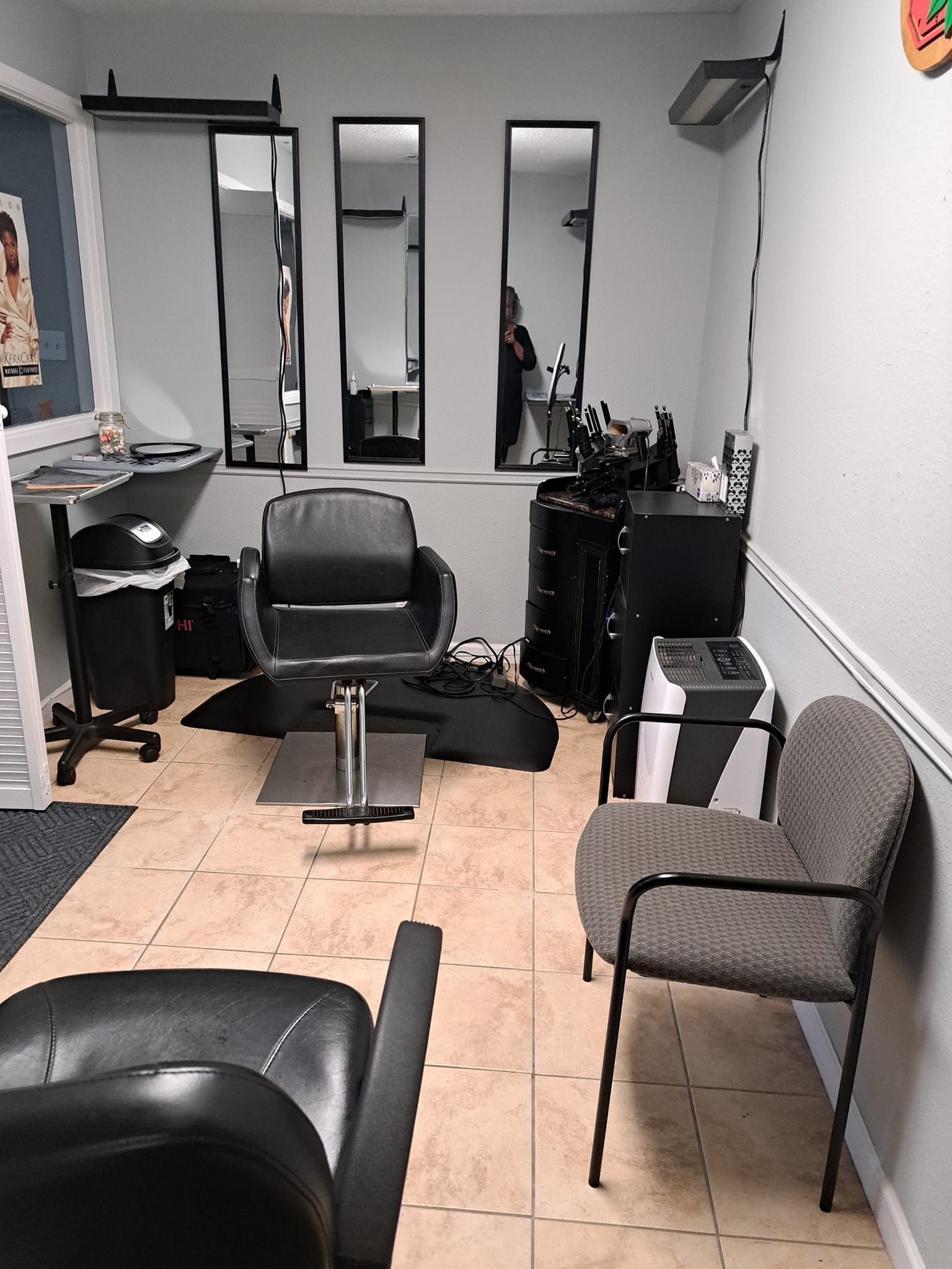 A small hair salon with chairs, mirrors, and styling tools on the floor.