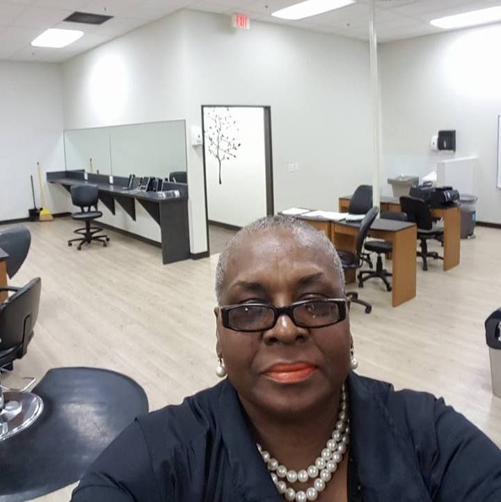 Woman with glasses and pearl necklace in salon, taking a selfie.