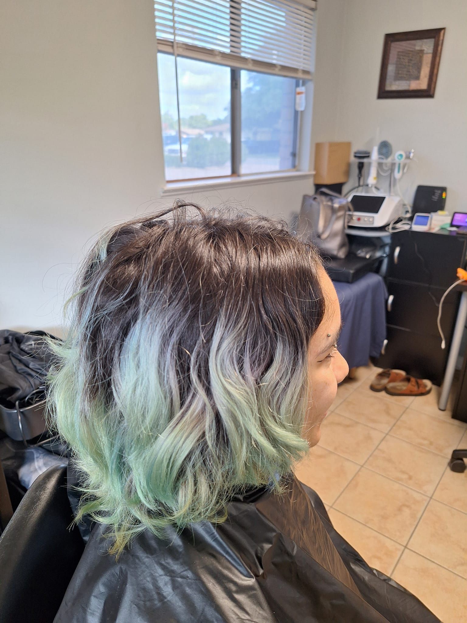Woman with dark hair, green tips, in salon.