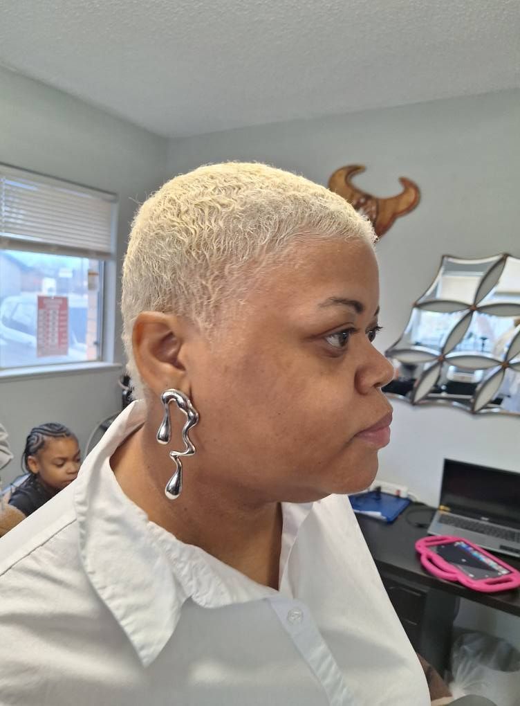 Woman with short blonde hair wearing silver earrings, indoors.