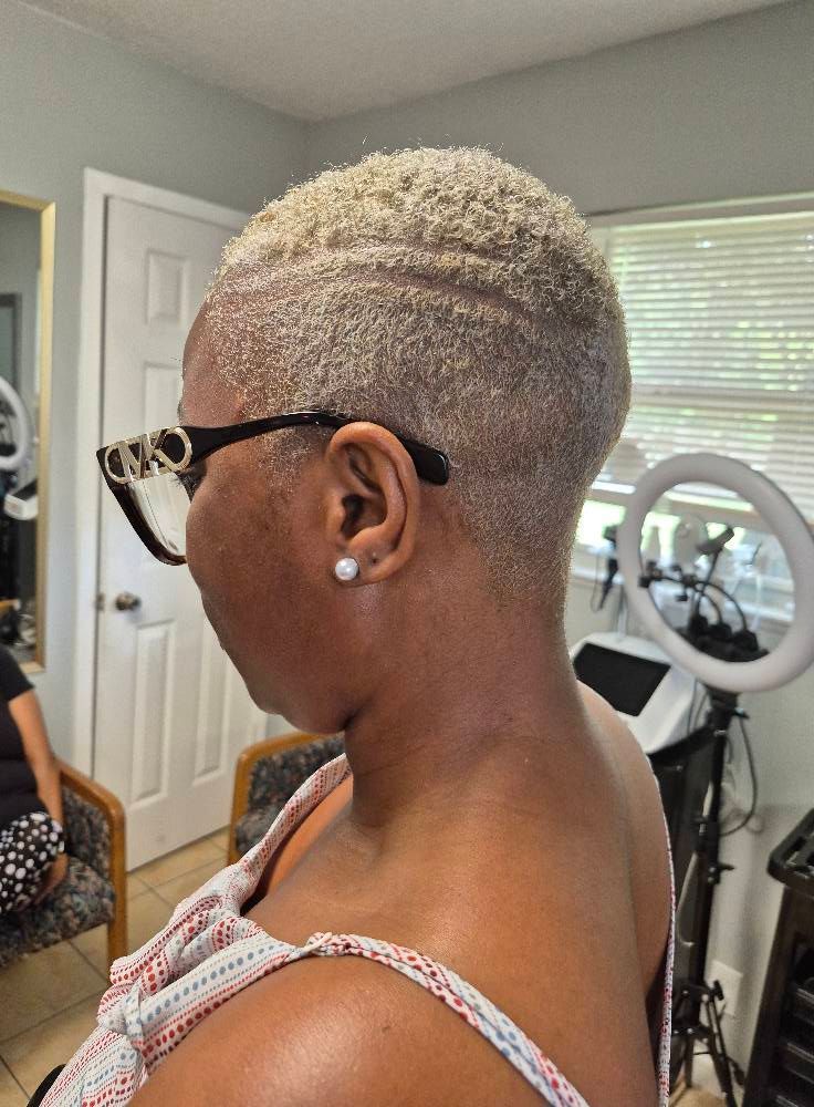 Woman with short, light-colored hair, wearing glasses, in a salon setting.