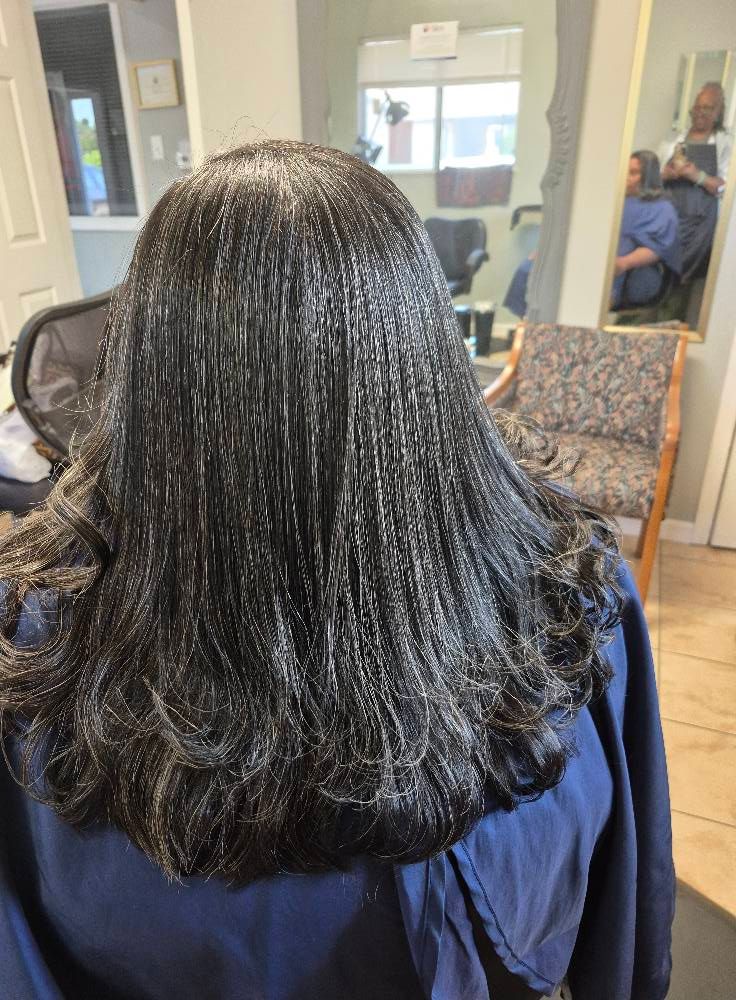 Black hair, straightened, styled in a salon, wavy ends.