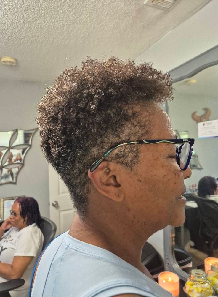 Woman with curly, short hair and glasses at a salon, profile view.