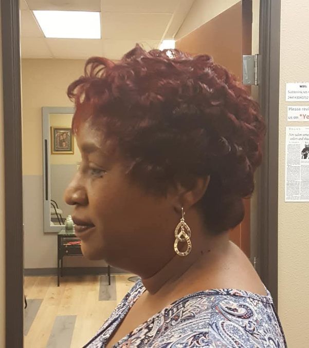Woman with red curly hair wearing gold earrings, looking to the side in a room.