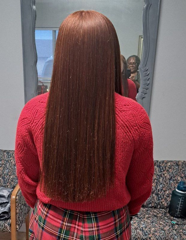 Person with long, dark, dreadlocks in a salon, facing away from the camera.