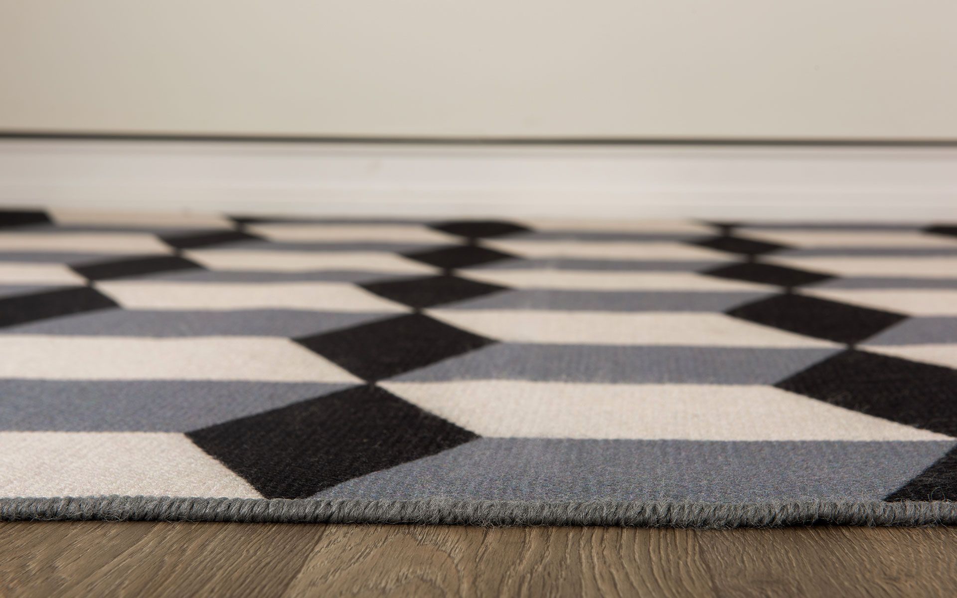 Geometric rug with black, gray, and white diamond shapes on a wooden floor.