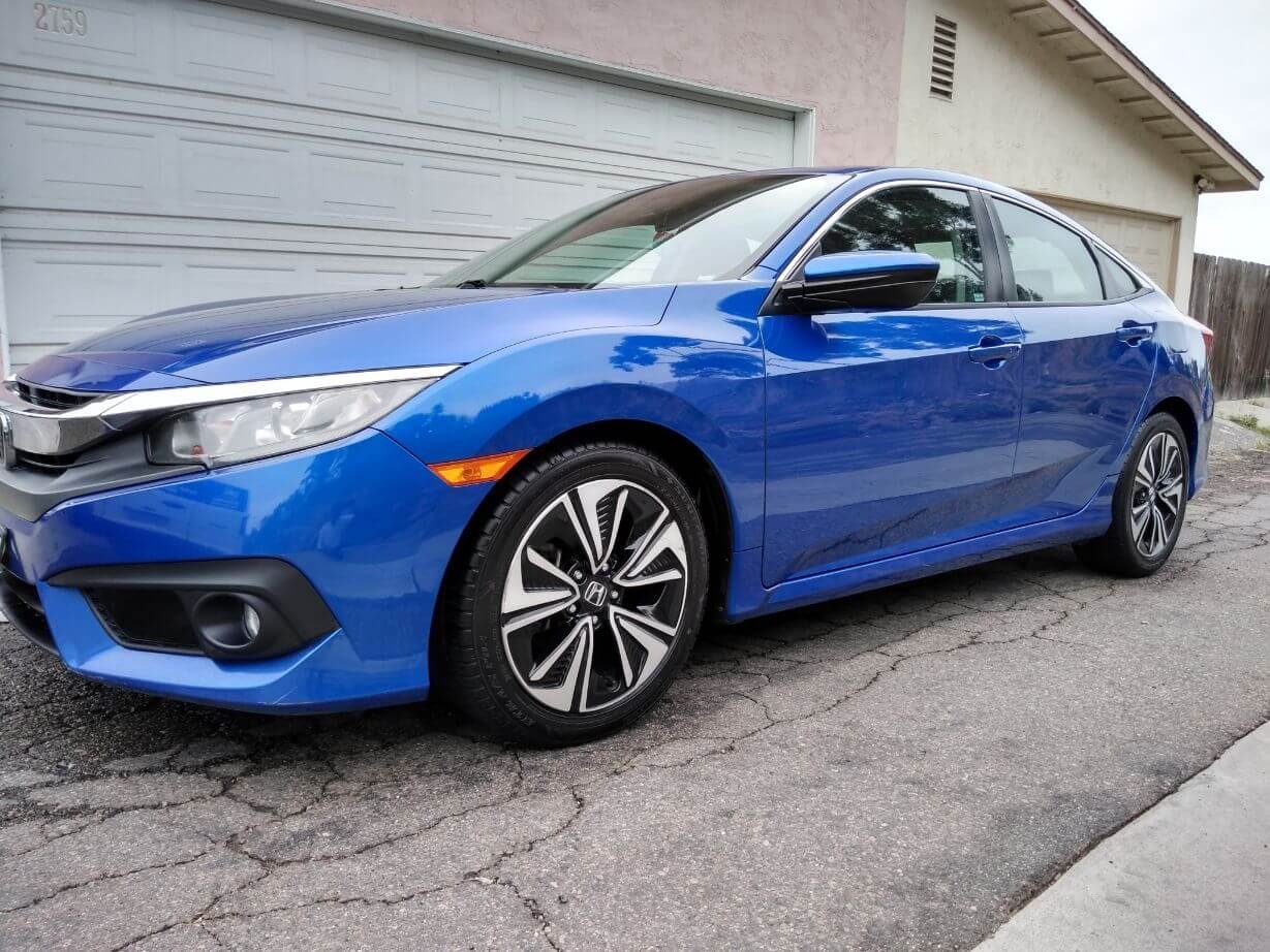 a blue honda civic is parked in front of a garage .